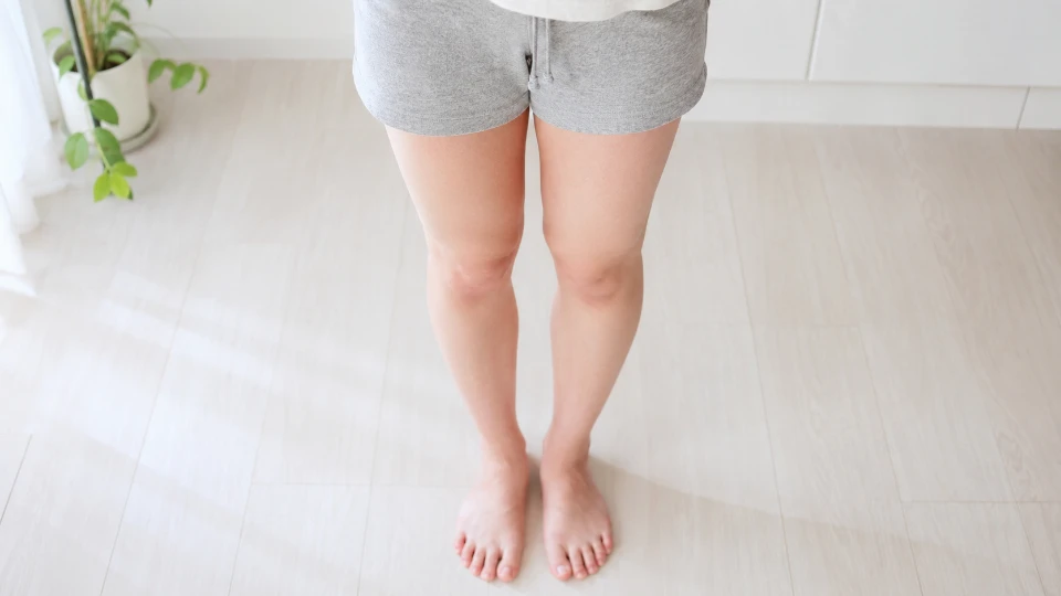 まっすぐ立ち、自分の両脚のラインを見下ろして確かめる日本人女性の脚(顔は写していない)
